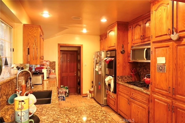 kitchen with sink, light stone counters, tasteful backsplash, and appliances with stainless steel finishes