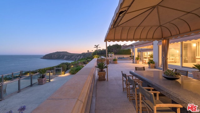 patio terrace at dusk featuring an outdoor bar and a water and mountain view