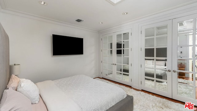 bedroom with hardwood / wood-style floors, crown molding, and french doors