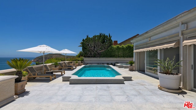 view of pool with a patio area and a water view