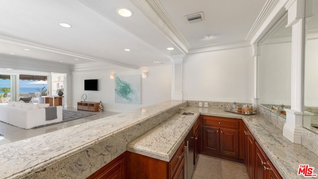 bar featuring crown molding, light stone counters, sink, and ornate columns