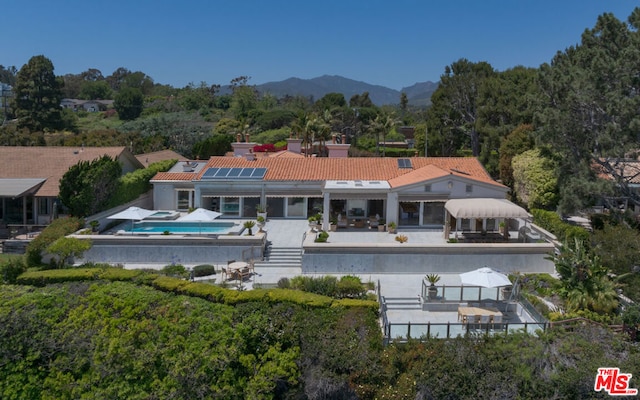 rear view of property with a mountain view, solar panels, and a patio