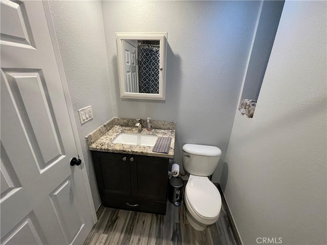 bathroom with vanity, toilet, and hardwood / wood-style floors