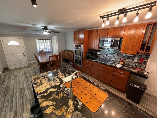 kitchen with a textured ceiling, dark wood-type flooring, stainless steel appliances, backsplash, and ceiling fan