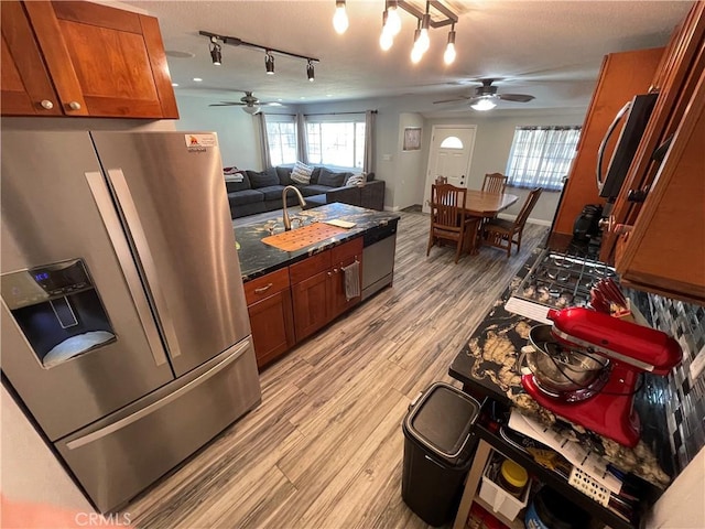 kitchen featuring ceiling fan, appliances with stainless steel finishes, sink, dark stone counters, and light hardwood / wood-style floors