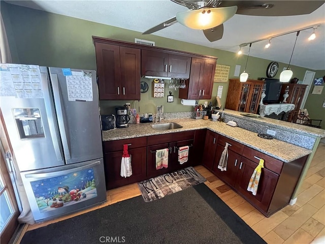 kitchen with kitchen peninsula, stainless steel refrigerator with ice dispenser, pendant lighting, ceiling fan, and sink