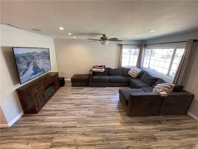 living room with ceiling fan, a fireplace, and a textured ceiling