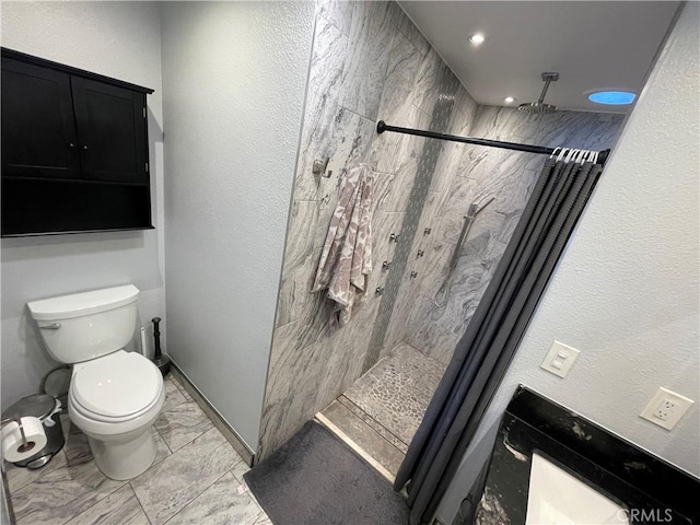 bathroom featuring tiled shower and toilet