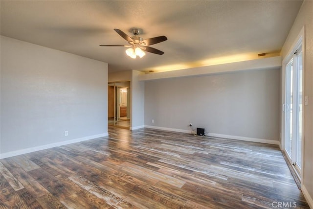 empty room featuring a ceiling fan, dark wood-style flooring, and baseboards