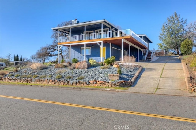 view of front of property with a deck, stairway, and driveway