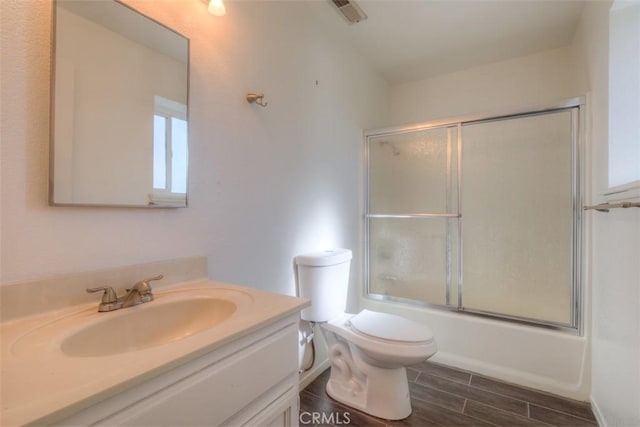 full bathroom featuring bath / shower combo with glass door, toilet, and vanity