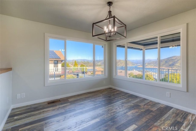 unfurnished dining area with a mountain view, a chandelier, and dark hardwood / wood-style flooring