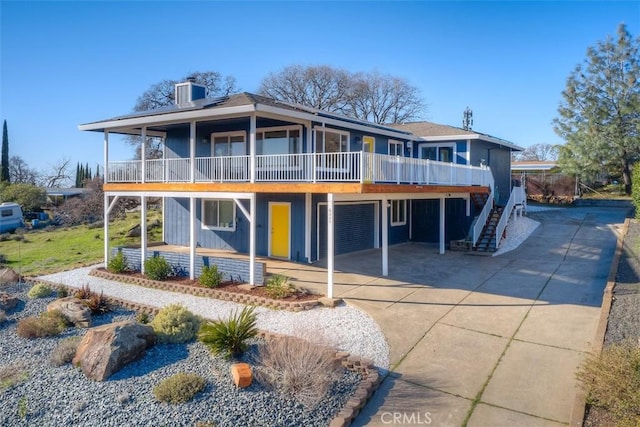 view of front of home featuring a wooden deck, stairway, a chimney, concrete driveway, and an attached garage