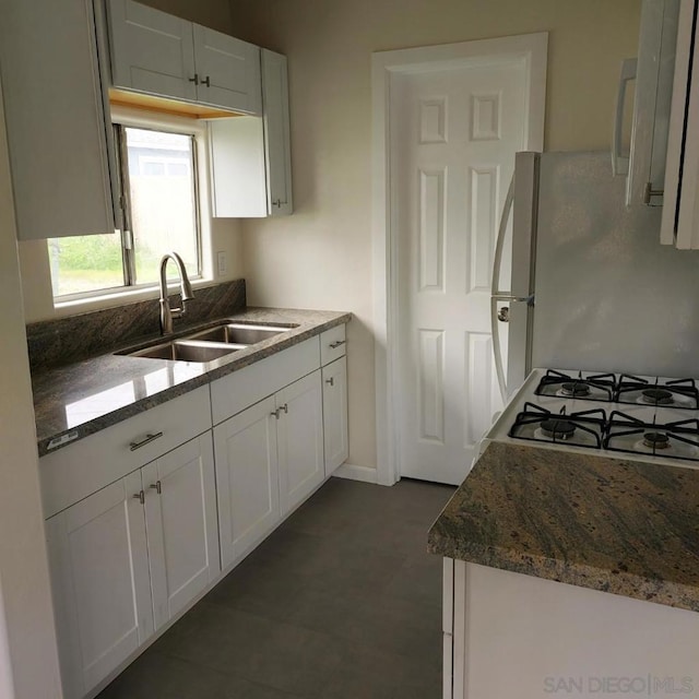 kitchen featuring sink, dark stone countertops, white appliances, and white cabinets