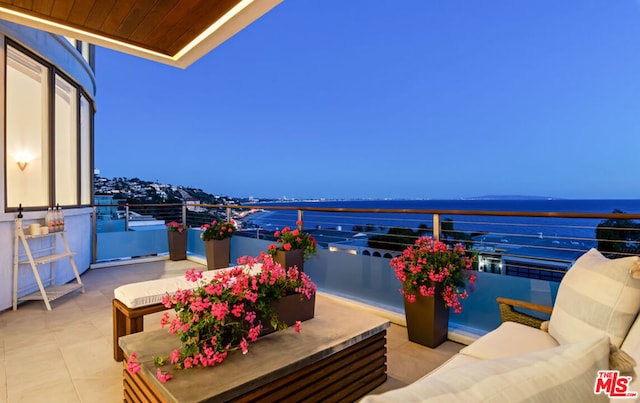 patio terrace at dusk with a balcony and a water view