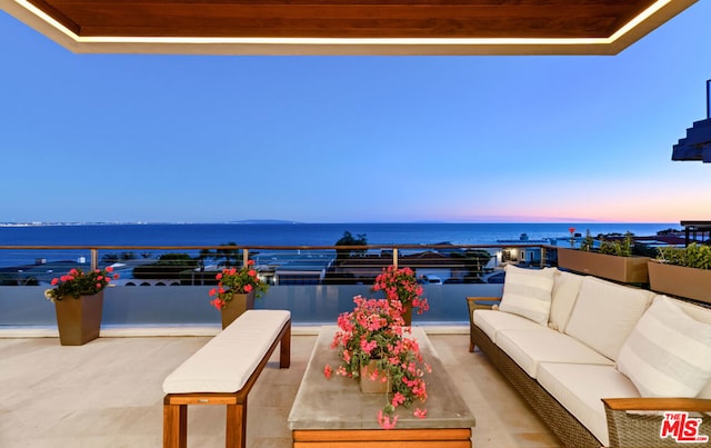 patio terrace at dusk with outdoor lounge area and a water view