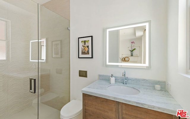 bathroom with toilet, an enclosed shower, and vanity