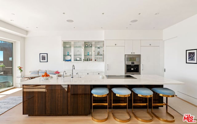 kitchen featuring a large island, white cabinetry, black electric cooktop, and light wood-type flooring