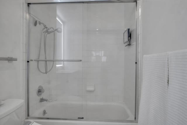 bathroom featuring bath / shower combo with glass door and toilet