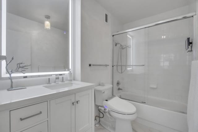 full bathroom featuring bath / shower combo with glass door, vanity, and toilet