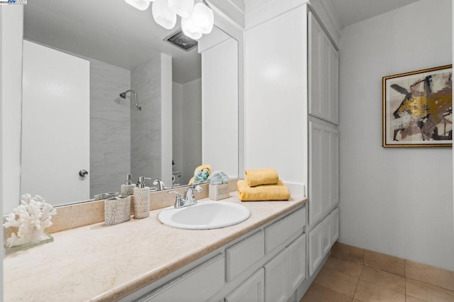 bathroom with vanity, tiled shower, and tile patterned flooring