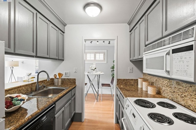 kitchen with sink, white appliances, gray cabinetry, and dark stone counters