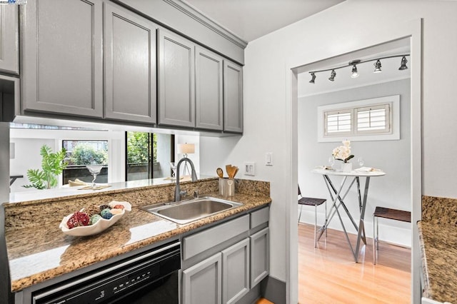 kitchen with black dishwasher, dark stone counters, a healthy amount of sunlight, sink, and gray cabinetry