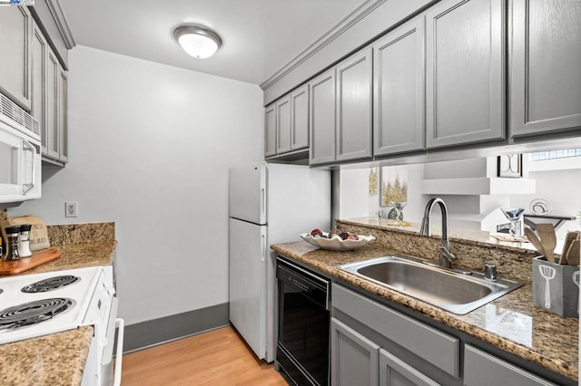 kitchen with white appliances, sink, light hardwood / wood-style flooring, dark stone counters, and gray cabinets