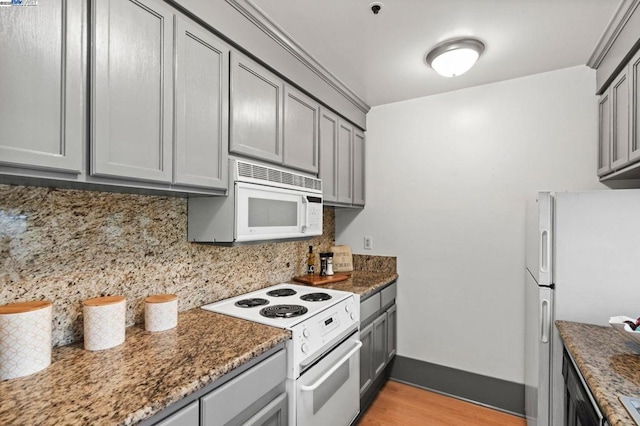 kitchen with gray cabinets, backsplash, white appliances, and dark stone counters