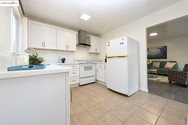 kitchen with white cabinets, white appliances, light tile patterned floors, and wall chimney exhaust hood