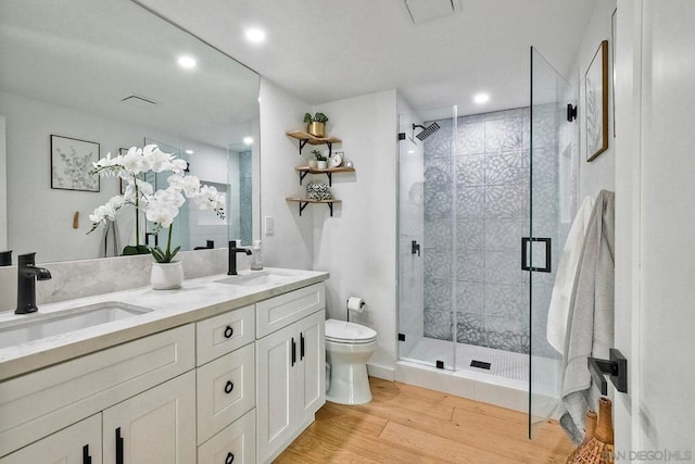 bathroom featuring hardwood / wood-style flooring, toilet, a shower with door, and vanity