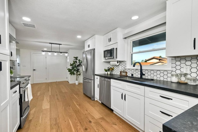 kitchen with light hardwood / wood-style floors, white cabinets, sink, backsplash, and stainless steel appliances