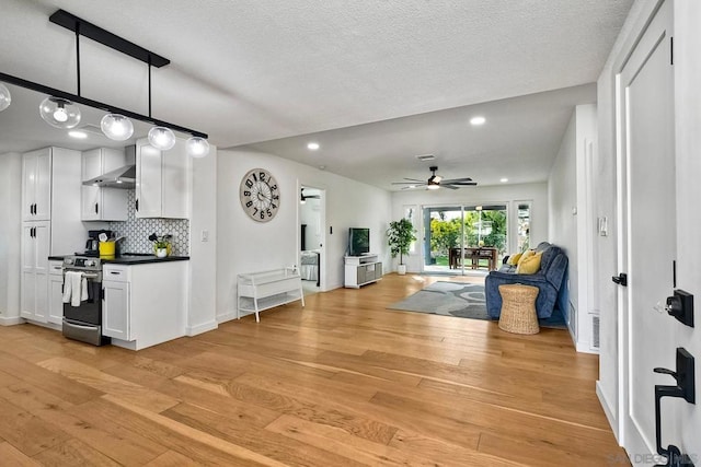 living room featuring ceiling fan, light hardwood / wood-style floors, and a textured ceiling