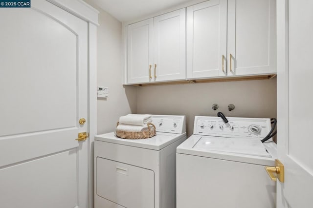 laundry area with separate washer and dryer and cabinets