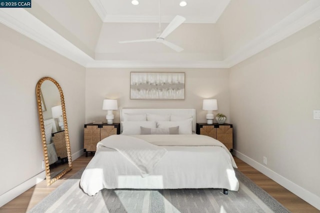 bedroom featuring ornamental molding, hardwood / wood-style floors, ceiling fan, and a tray ceiling