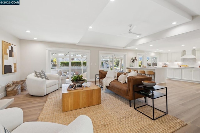 living room with lofted ceiling, ceiling fan, and light wood-type flooring