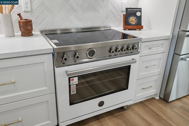 kitchen with stainless steel fridge, high end white range, tasteful backsplash, white cabinets, and light wood-type flooring