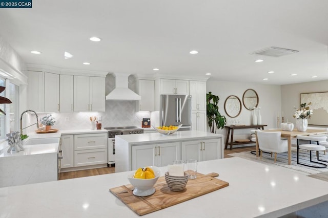 kitchen with sink, white cabinetry, stainless steel appliances, decorative backsplash, and wall chimney exhaust hood