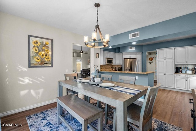 dining area featuring dark wood-type flooring and ceiling fan with notable chandelier