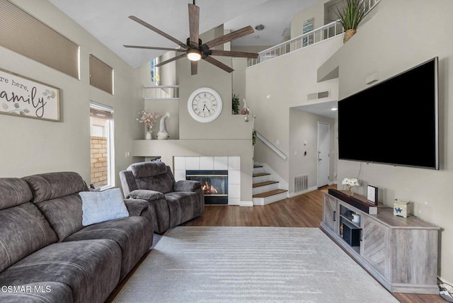 living room featuring ceiling fan, high vaulted ceiling, dark hardwood / wood-style floors, and a fireplace