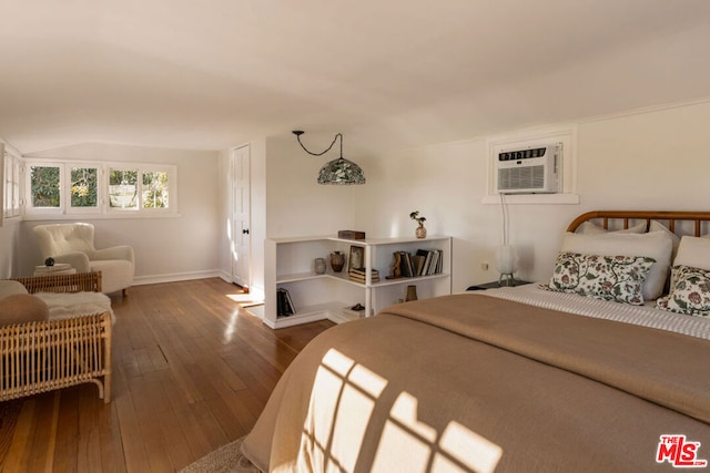 bedroom featuring hardwood / wood-style floors, vaulted ceiling, and an AC wall unit