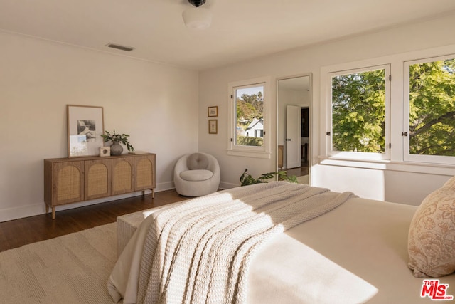 bedroom with multiple windows and dark hardwood / wood-style flooring