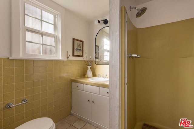 bathroom with vanity, toilet, tile walls, and tile patterned flooring