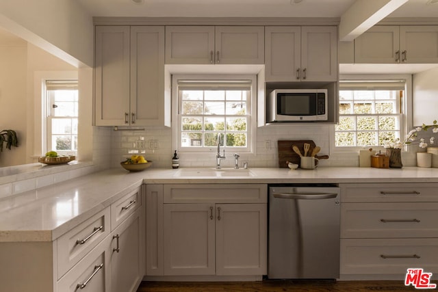 kitchen featuring sink, light stone counters, tasteful backsplash, and appliances with stainless steel finishes