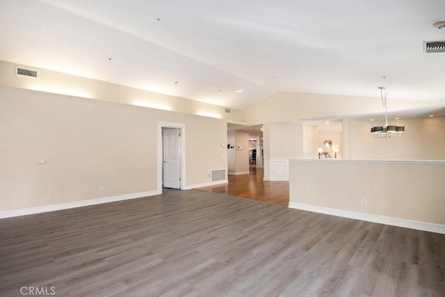 unfurnished living room featuring a notable chandelier, wood-type flooring, and vaulted ceiling