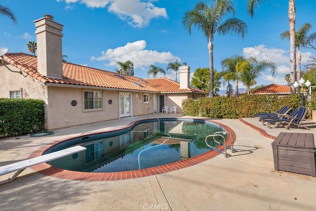 view of pool with a patio, a diving board, and french doors