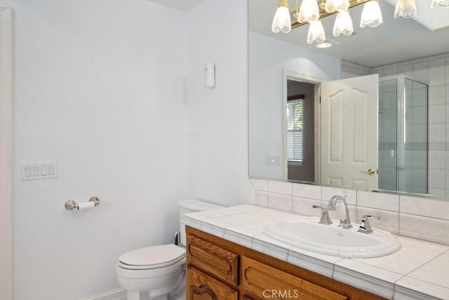 bathroom featuring toilet, vanity, backsplash, and walk in shower