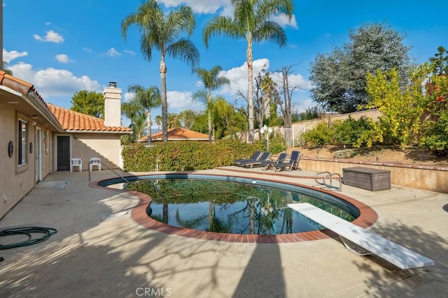 view of swimming pool featuring a diving board and a patio