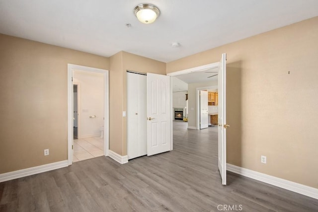 unfurnished bedroom with connected bathroom, light hardwood / wood-style floors, and a closet