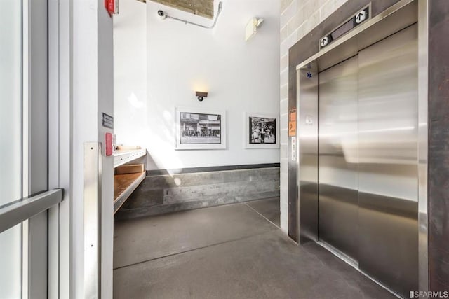 bathroom with elevator and concrete flooring